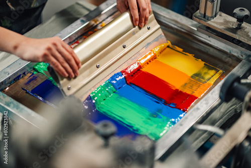 Fotografia Graphic technician's hands silkscreen printing with squeegee.
