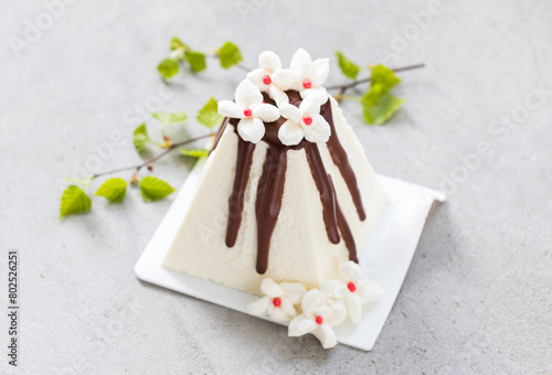Easter Holiday. Ricotta cream dessert with chocolate. Decorated with white marshmallow flowers. With birch twigs. On a plate. Close-up