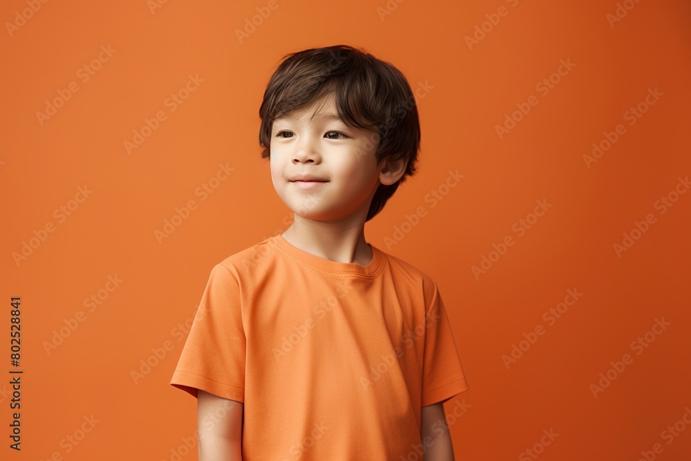 A young boy in an orange shirt is smiling at the camera A young boy in an orange shirt is smiling at the camera