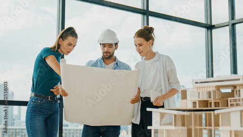 Professional architect engineer team talking, sharing, brainstorming about design while manager hold at project plan. Young architect holding plan while manager listen and point at plan. Tracery © Summit Art Creations