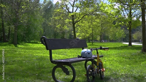 Zoom in view of the bicycle and helmet near the bench in the park