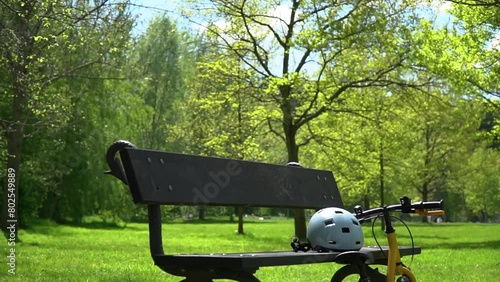 Zoom in view of the bicycle and helmet near the bench in the park
