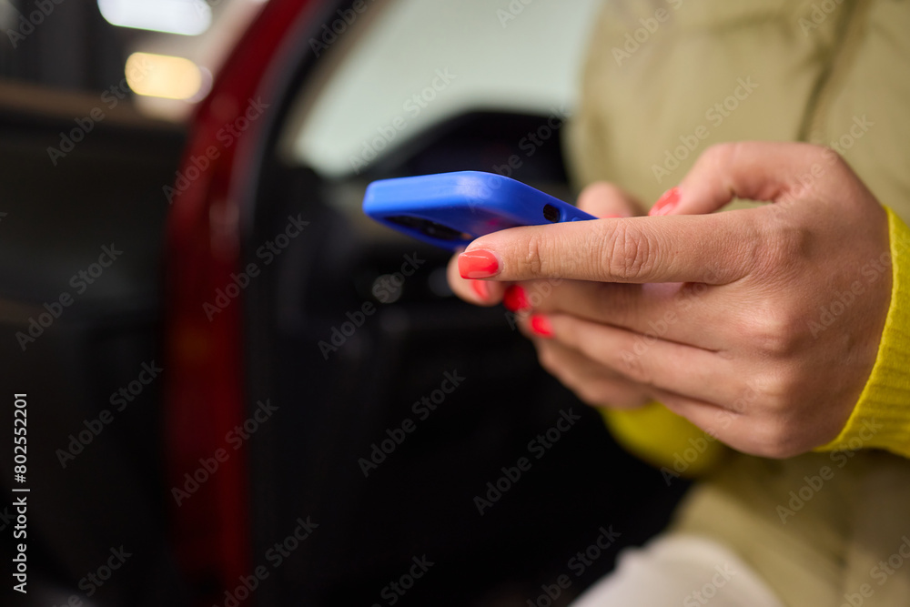Naklejka premium A woman shows an electric blue cell phone with red nails, in a stylish gesture
