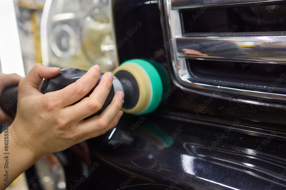 Person using machine to polish black cars automotive exterior Person using machine to polish black cars automotive exterior