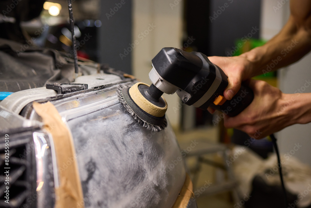 Person using a machine to polish automotive lighting on a car headlight Person using a machine to polish automotive lighting on a car headlight