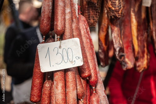Selective blur on cajna kobasica sausages spiked for sale with a price of 1300 on stand of a serbian market. Cajna kobasica, or tea sausage, is a traditional serbian sausage made of smoked cured pork. photo