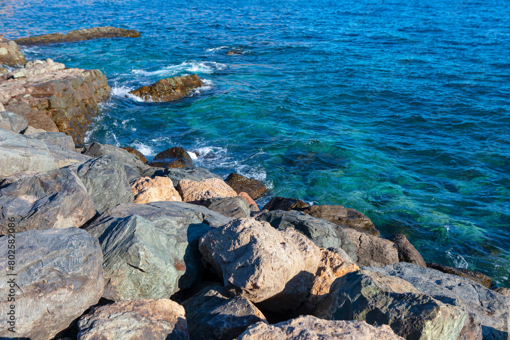 Rocky coast and turquoise water on a sunny day. Rocks on the shore contrasts with the deep blue sea Rocky coast and turquoise water on a sunny day. Rocks on the shore contrasts with the deep blue sea