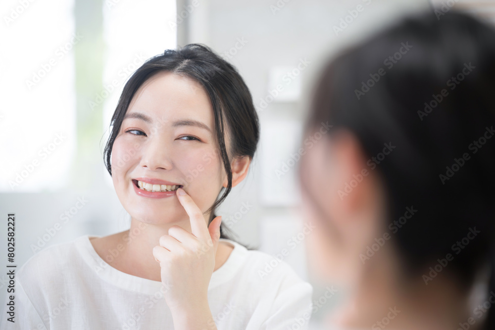 Cute woman looking at her teeth and whiteness while looking in the mirror Whitening, etc. Close-up