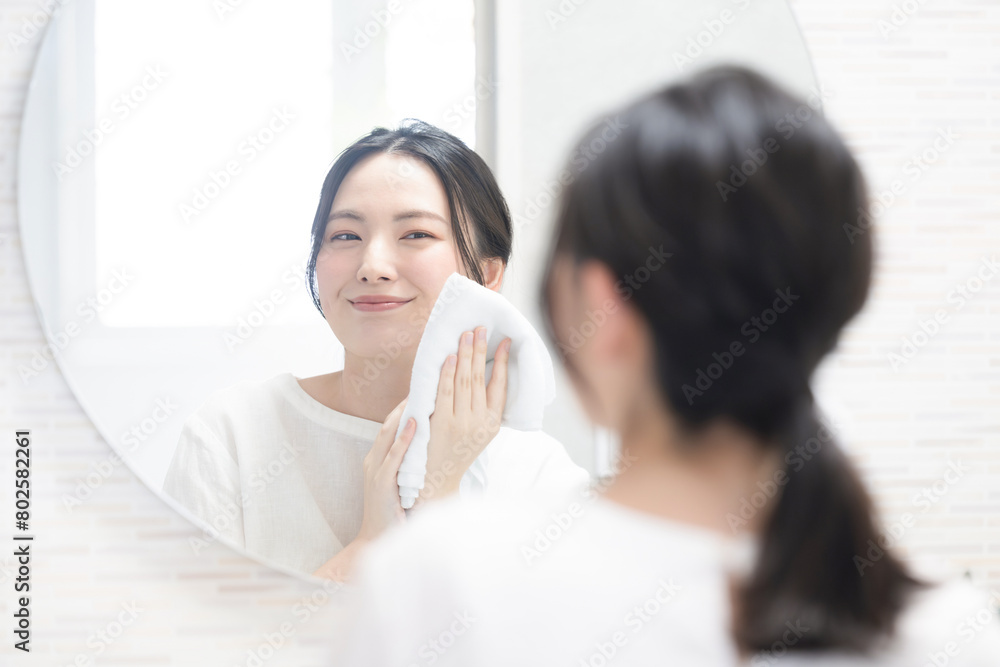 Woman holding towel and washing face in washbasin mirror Close-up Woman holding towel and washing face in washbasin mirror Close-up