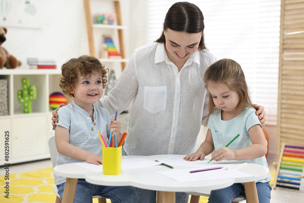 Mother and her little children drawing with colorful pencils at home Mother and her little children drawing with colorful pencils at home