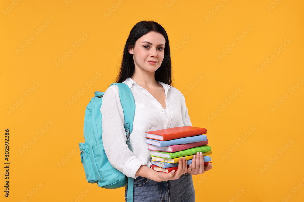 Student with stack of books on yellow background Student with stack of books on yellow background