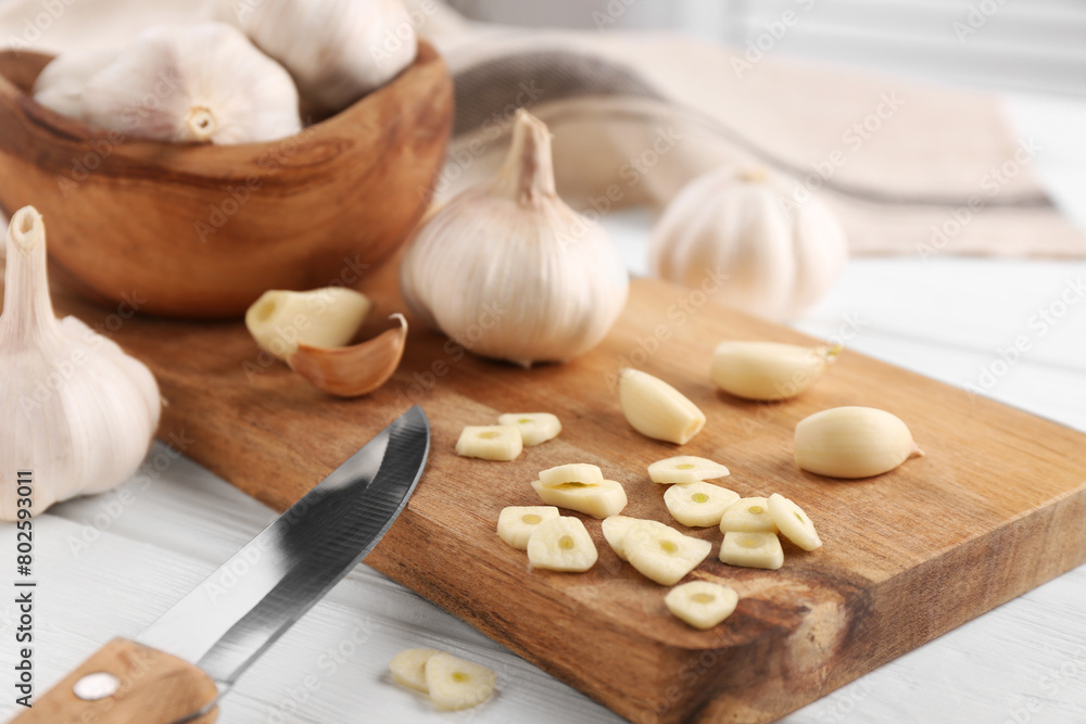 Aromatic cut garlic, cloves, bulbs and knife on white wooden table, closeup Aromatic cut garlic, cloves, bulbs and knife on white wooden table, closeup