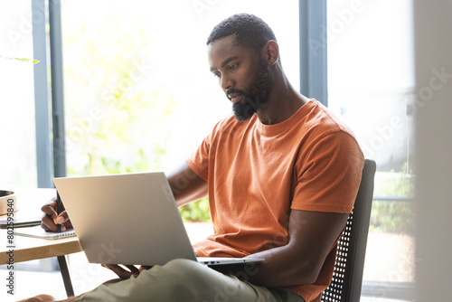 African American male homeowner sitting, using laptop photo