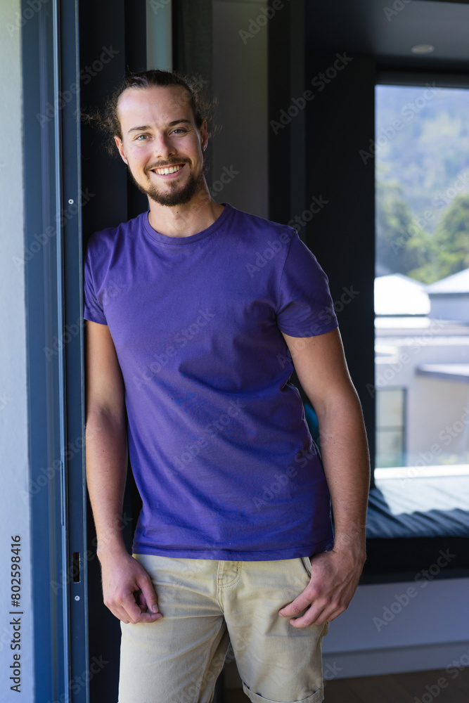 Caucasian young man standing at doorway, smiling, at home Caucasian young man standing at doorway, smiling, at home