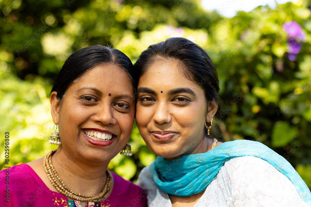Indian mother and teenage daughter smiling together in garden Indian mother and teenage daughter smiling together in garden