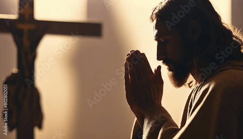 Silhouette of jesus praying to cross  warm tones 