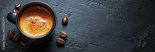 A cup of coffee seen from above on a plain black table top.  photo