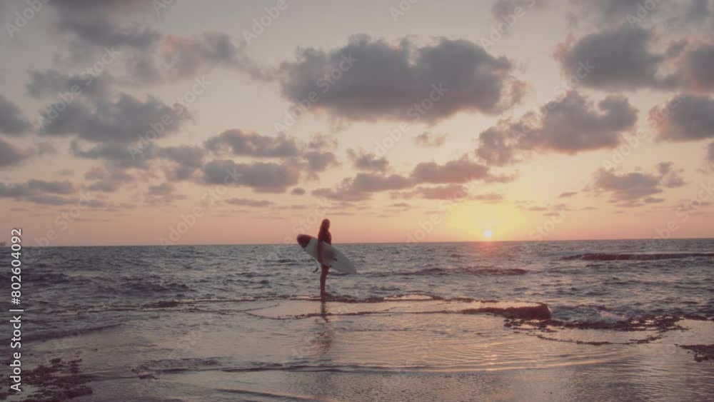 Man standing by the water at sunset with a surfboard Man standing by the water at sunset with a surfboard