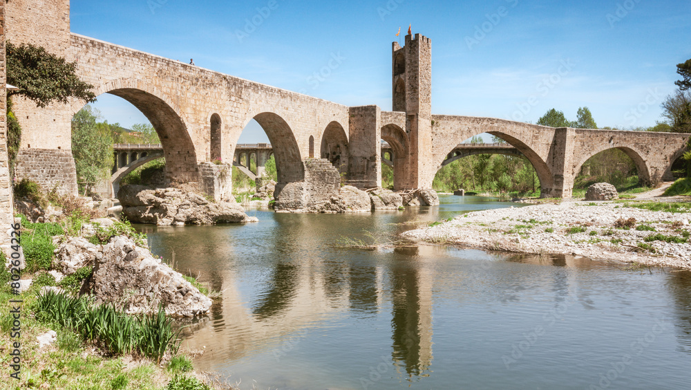 The medieval bridge of Besalú, Girona, is reflected on a river. The medieval bridge of Besalú, Girona, is reflected on a river.