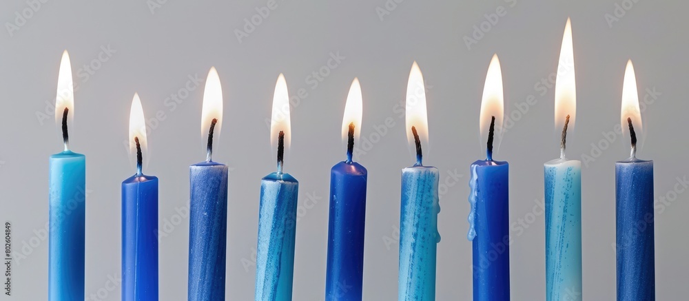 Blue candles with lit flames on a light gray background for a birthday celebration.