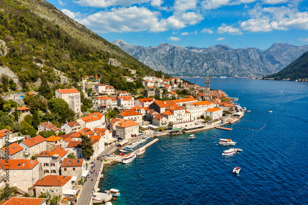 Fototapeta premium View of the historic town of Perast at famous Bay of Kotor on a beautiful sunny day with blue sky and clouds in summer, Montenegro. Historic city of Perast at Bay of Kotor in summer, Montenegro.