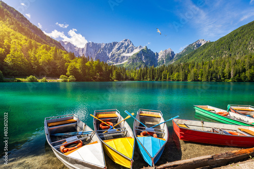 Picturesque lake Lago Fusine with colorful boats. Fusine lake with Mangart peak on background. Popular travel destination of Julian Alps. Location: Tarvisio comune , Province of Udine, Italy, Europe. photo