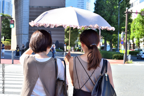 信号で二人で日傘をさす女性たち