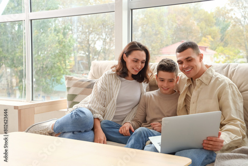 Little boy with his parents using laptop on couch at home © Pixel-Shot