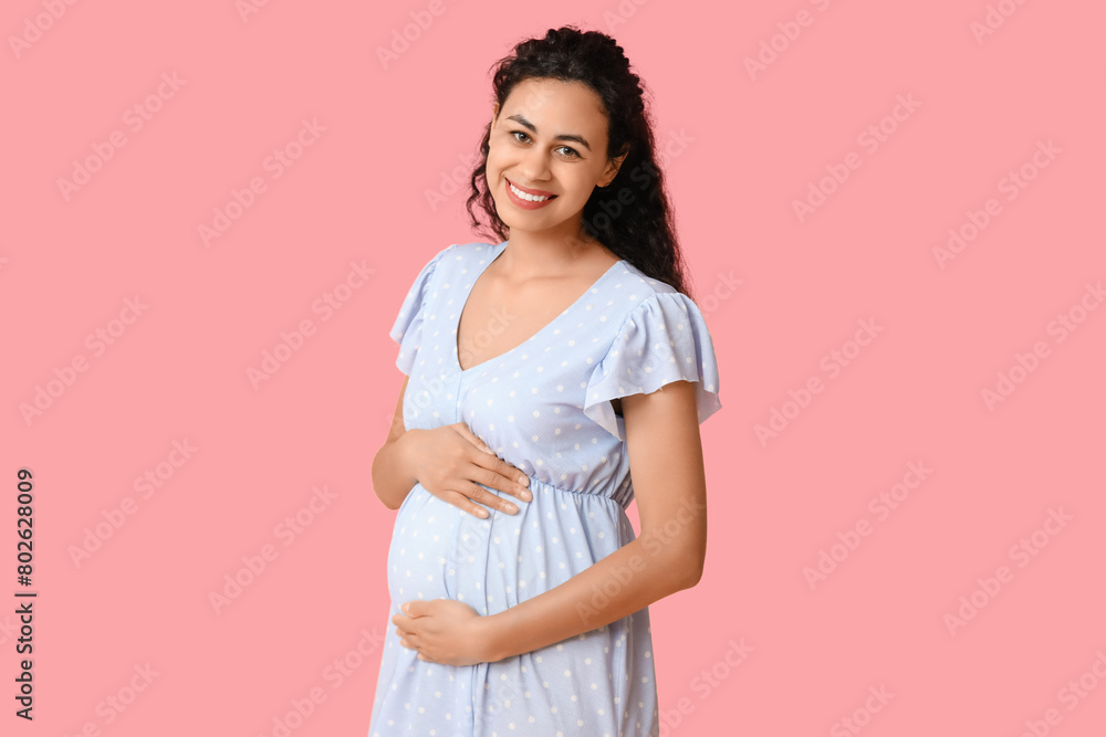Happy young pregnant African-American woman on pink background Happy young pregnant African-American woman on pink background