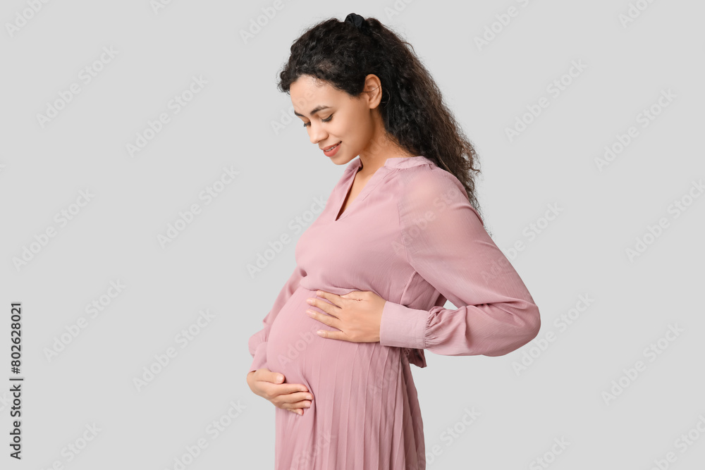 Beautiful young pregnant African-American woman on grey background Beautiful young pregnant African-American woman on grey background