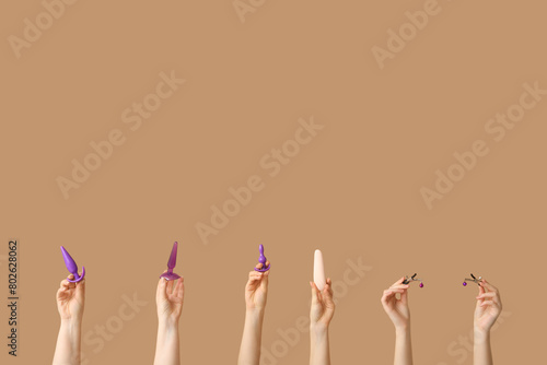 Female hands with different sex toys against color background