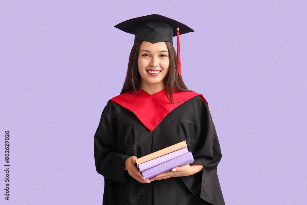 Young female graduate with books on lilac background Young female graduate with books on lilac background