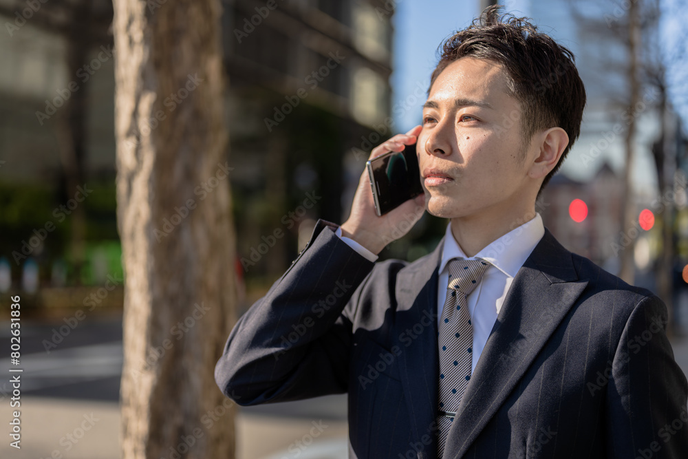日差しを浴びながら電話するビジネスマン