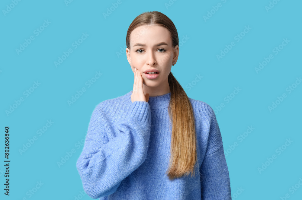 Young woman suffering from toothache on blue background Young woman suffering from toothache on blue background