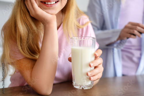 Mother and happy daughter with cup of milk in kitchen at home  closeup