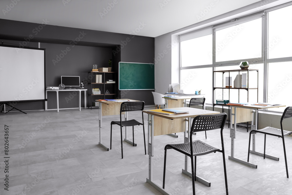 Interior of empty classroom with desks and chalkboard Interior of empty classroom with desks and chalkboard