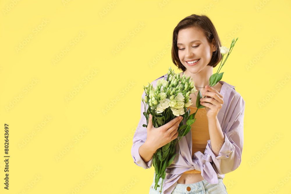 Young woman with eustoma flowers on yellow background