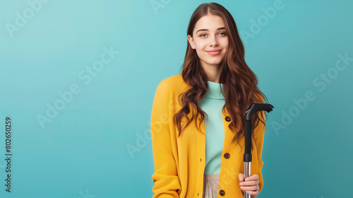 young woman disability advocate holding walking stick, isolated on plain blue color studio background with copy space 