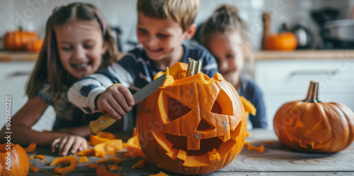 Close-up of children carving Halloween pumpkin with knife on wooden table at home, surrounded by pumpkins in kitchen photo