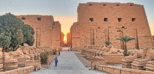 Golden glow of the rising sun rise illuminates the main axis of the Temple of Karnak with ram headed sphinxes lining the front entrance at the temple complex dedicated to God Amun-Re in Luxor,Egypt photo