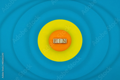 丸い黄色のFINの英語ブロックから波紋が広がる水色の背景 photo