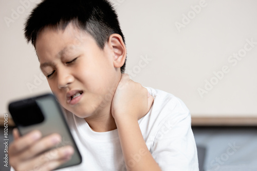 Asian boy looking at phone screen,tilting his head down for long time,Text Neck Syndrome,Smartphone or Mobile syndrome,stiff and pain in neck muscle,aching and tightness in nape of neck and shoulder