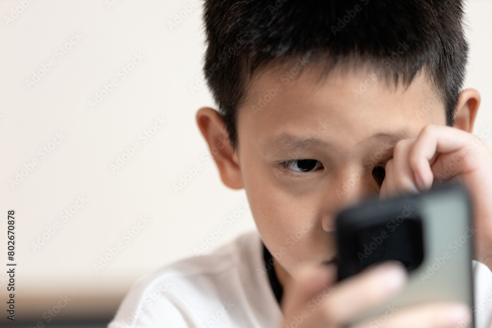 Wall Mural Child boy looking phone screen,unable to see clearly,Amblyopia disease,blurred v