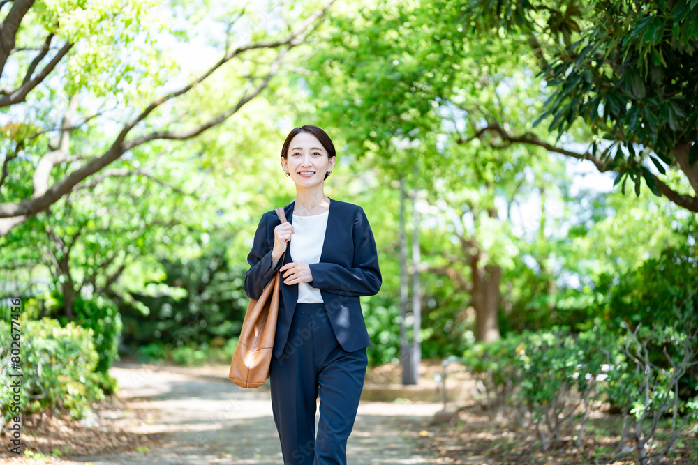 新緑を歩くスーツを着た女性 新緑を歩くスーツを着た女性