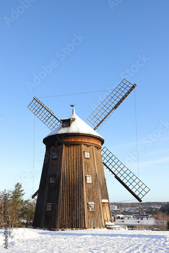 A wooden  smock mill type of  windmill in a winter scene.
