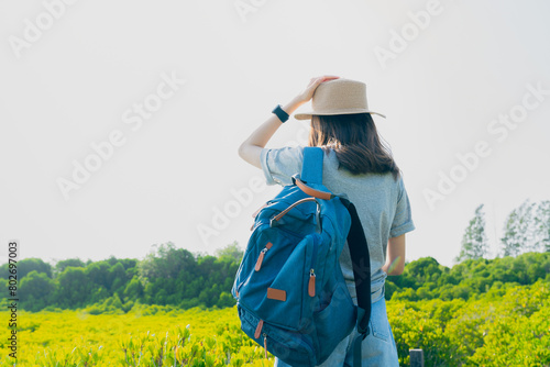 Woman standing on a bridge in the garden and hand touch hat on head with breaths a full breast and enjoys freedom. Summer time concept.