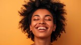 African American woman with closed eyes laughing on a peach background