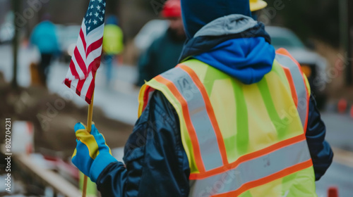 safety vest worker holding american flag