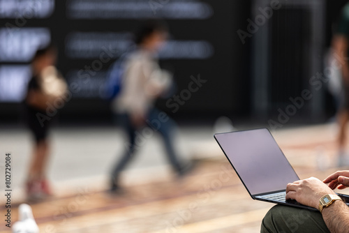 Working Remotely - A man works on his laptop in an urban outdoor setting