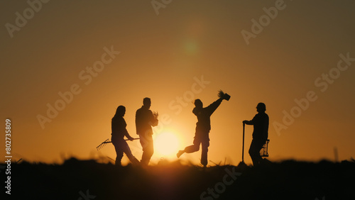 A group of cheerful farmers dancing in a field at sunset